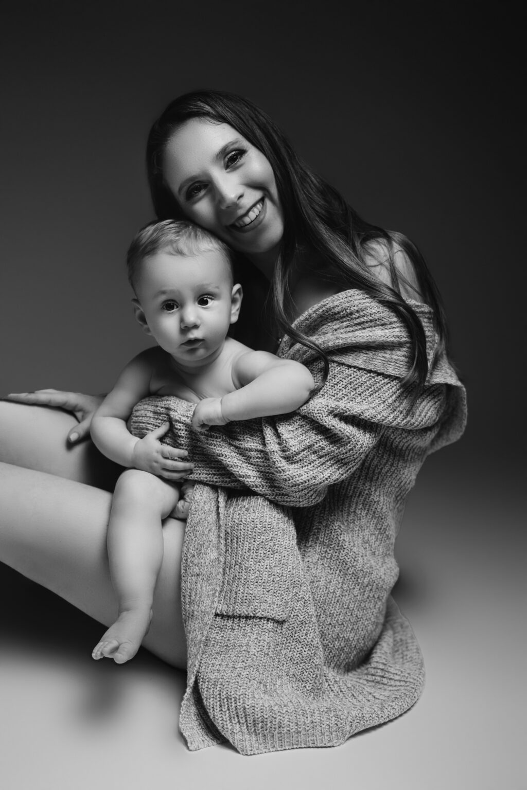 Mamm am Strëckcardigan mam Baby um Schouss