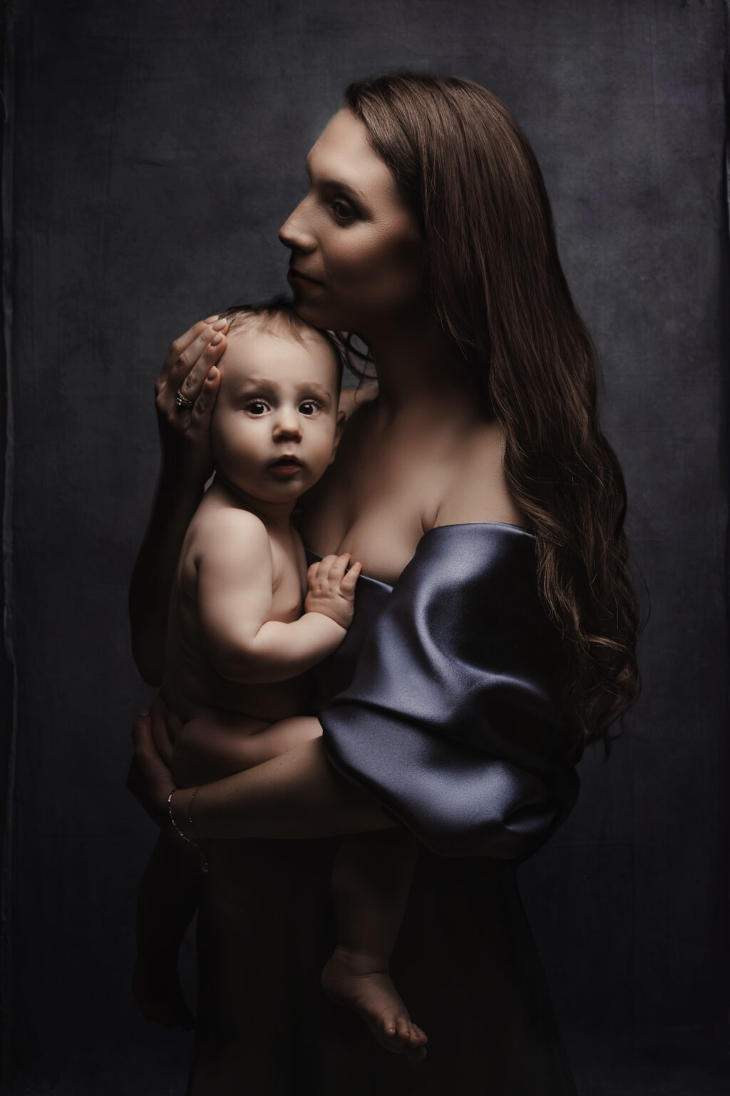 Mamm am gro-bloe Satin mat hirem Baby um Aarm